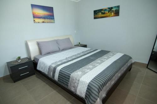 a bedroom with a bed and a nightstand and two pictures at KALLIOPIs HOUSE in Paralia Katerinis