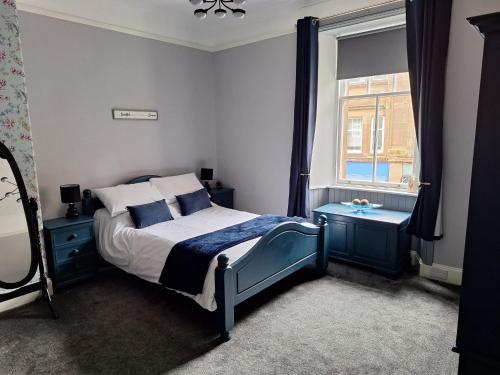a bedroom with a bed with blue furniture and a window at The Nifty Nook in Campbeltown