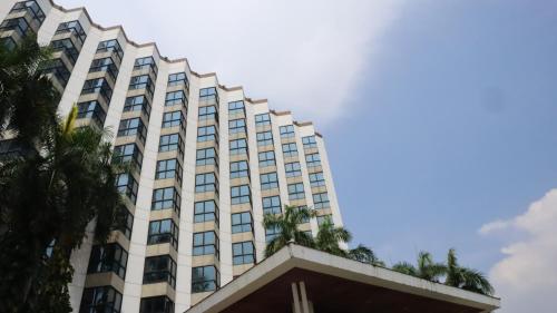 a tall building with palm trees in front of it at Napalai Hotel in Udon Thani