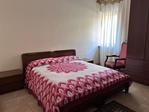 a bedroom with a bed with a pink and white comforter at Villa Vanessa in Spoltore