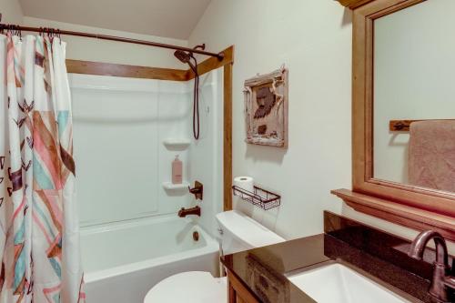 a bathroom with a sink and a toilet and a mirror at On the Flathead River! Rustic Saloon-Themed Cabin in Columbia Falls