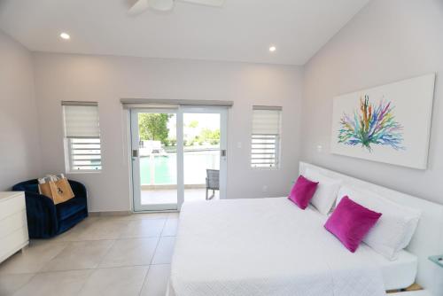 a bedroom with a white bed with pink pillows at 246D South Finger in Jolly Harbour