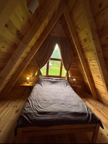a bed in a wooden room with a window at Balic Inn in Gusinje