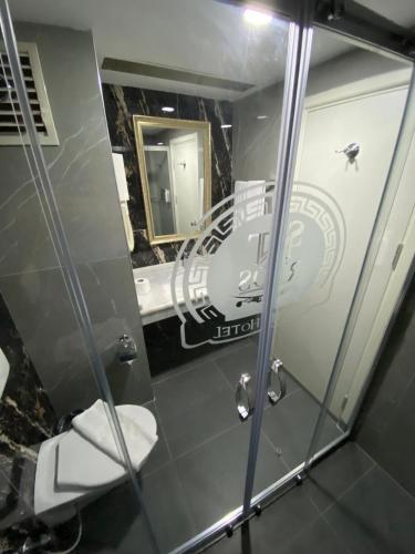 a bathroom with a shower with a toilet and a mirror at RİOS BEACH HOTEL in Beldibi