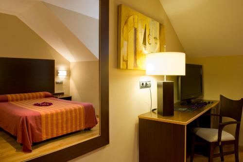 a bedroom with a bed and a desk with a television at SNÖ Hotel Ciudad de Sabiñánigo in Sabiñánigo