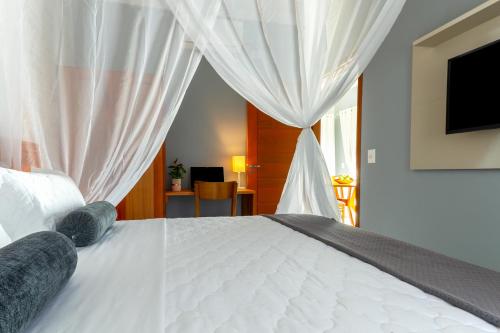 a bedroom with a white bed with curtains at Calamar Flats - Frente à Praia do Jabaquara in Paraty