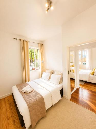a bedroom with a large white bed and a window at A Velha Casa Caboz in Ponta do Sol