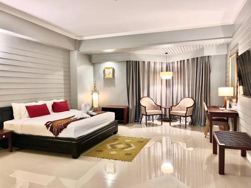 a bedroom with a bed and a table and chairs at Napalai Hotel in Udon Thani