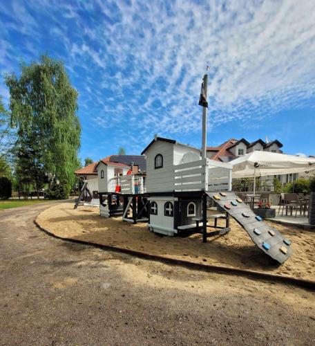 a playground with a slide in front of a house at Houseboat - Hotel Ukiel Wellness & SPA in Olsztyn