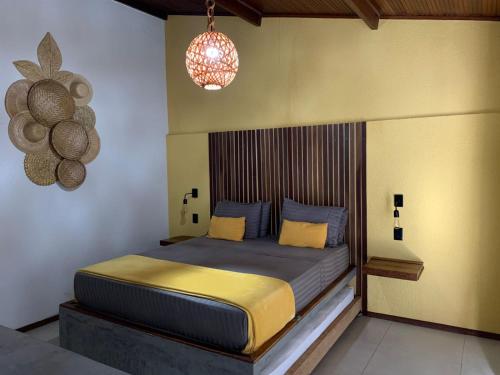 a bedroom with a bed with a wooden headboard at Jardim dos Milagres Suítes in São Miguel dos Milagres