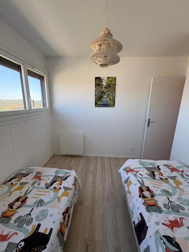 a bedroom with a bed and a chandelier at Lacanau-Océan Triplex Front de mer in Lacanau-Océan