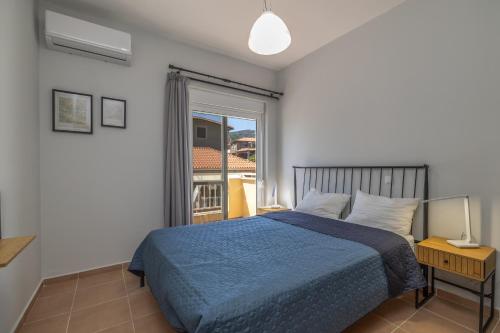 a bedroom with a blue bed and a window at Blue Skala - Indigo Apartment I in Skala