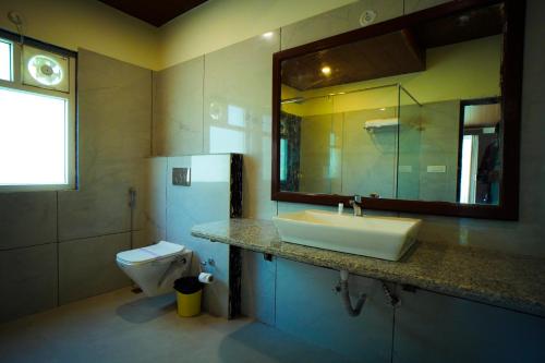 a bathroom with a sink and a toilet and a mirror at Mango Bloom River Resort By Excel Hotels & Resorts in Marchula
