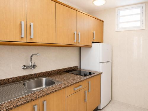 a kitchen with a sink and a white refrigerator at Apartamentos Tamaragua in Playa del Ingles