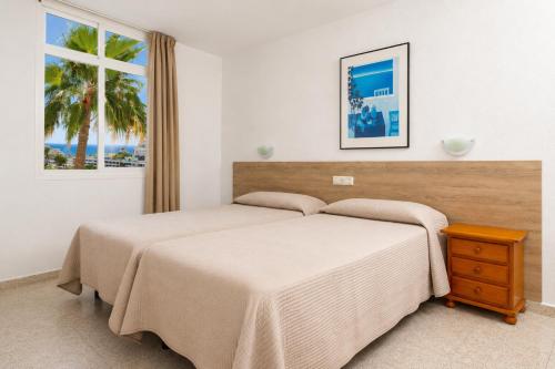 a bedroom with two beds and a window at Apartamentos Tamaragua in Playa del Ingles