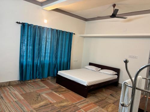 a bedroom with a bed and a blue curtain at Oceanbliss Villa in Pallipuram