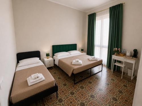 a hotel room with two beds and green curtains at Alba Mediterranea in Reggio di Calabria