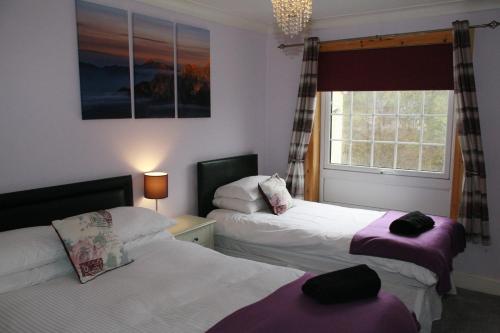 1 dormitorio con 2 camas y ventana en Glenlochy Nevis Bridge Apartments, en Fort William