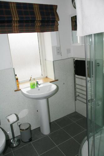 a bathroom with a sink and a toilet and a window at Glenlochy Nevis Bridge Apartments in Fort William