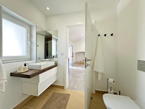 a white bathroom with a sink and a mirror at Casa do Miradouro in São Bartolomeu do Outeiro