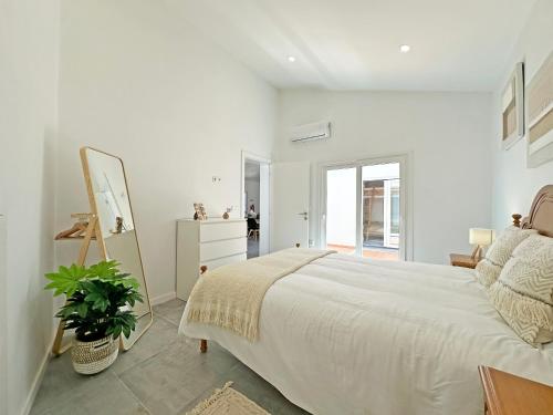 a white bedroom with a bed and a mirror at Casa do Miradouro in São Bartolomeu do Outeiro