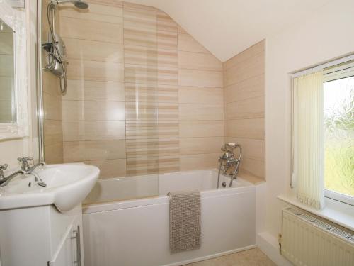 a bathroom with a white tub and a sink at Fron-Haul in Llansantffraid-ym-Mechain