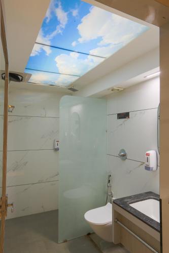 a bathroom with a toilet and a window at Hotel Shrimmaya, Ujjain in Ujjain