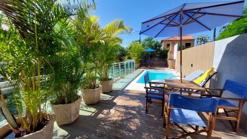 a patio with a table and chairs next to a pool at Village Itaúna Inn - Casas de Temporada in Saquarema