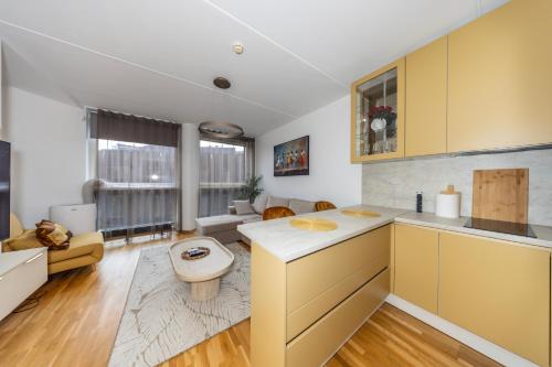 a kitchen with yellow cabinets and a living room at Bright Studio in Rotermann Quarter - Noor Apartment in Tallinn