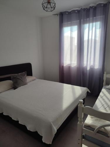 a bedroom with a white bed and a window at Dinos Apartments in Ulcinj