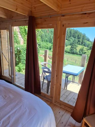 a room with a bed and a table on a deck at Cedre bleu in Saint-Racho