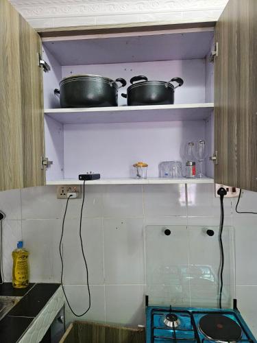 a kitchen with two pots on a shelf at Allan BnB HomaBay in Homa Bay