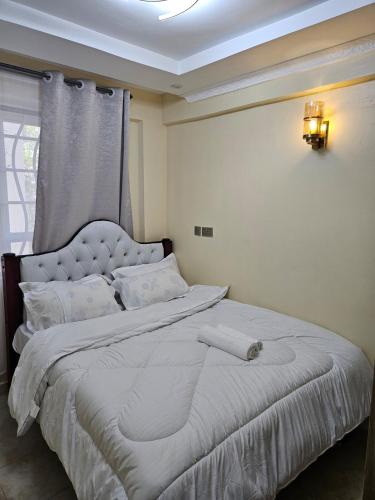 a white bed in a room with a window at Allan BnB HomaBay in Homa Bay