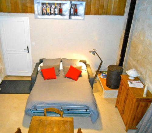a bedroom with a bed with red pillows on it at Sous les Marronniers in Petit-Palais-et-Cornemps