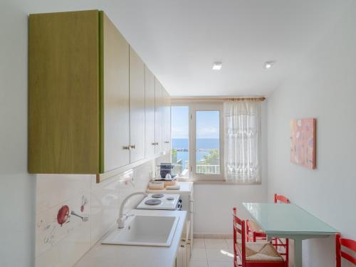 a kitchen with green cabinets and a sink and a table at Pension Votsi in Votsi