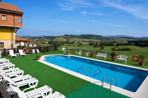 a swimming pool with white chairs at Apartamentos La Gloria in Santillana del Mar