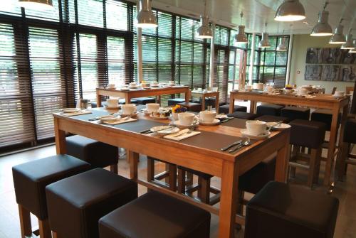 a dining room with tables and chairs and windows at Denham Grove in Denham