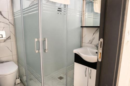 a bathroom with a shower and a toilet and a sink at Kent Pansiyon Ayvalık in Ayvalık