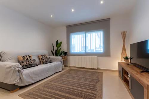 a living room with a couch and a flat screen tv at CASA AZUL Blanes in Blanes