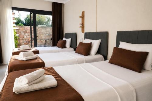 a hotel room with three beds with towels on them at Kent Pansiyon Ayvalık in Ayvalık