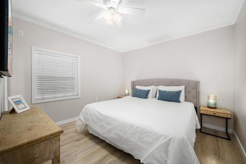 a white bedroom with a large bed with blue pillows at 1628 West Oceanfront Oasis 6 in Newport Beach