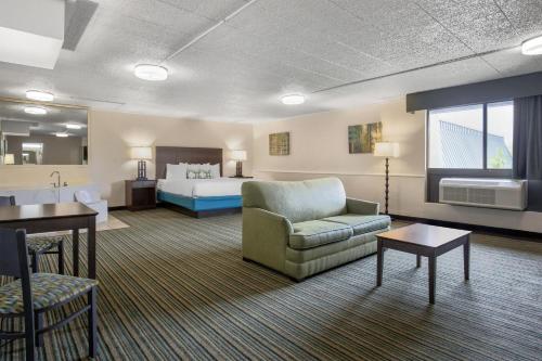 a hotel room with a bed and a couch and a chair at Best Western Woodhaven Inn in Woodhaven