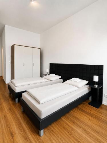 two beds in a room with wooden floors at Gauaz Boardinghouse in Maisach