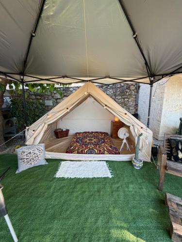 a tent with a bed in the middle of the grass at La Somavan Tambu in Xàtiva