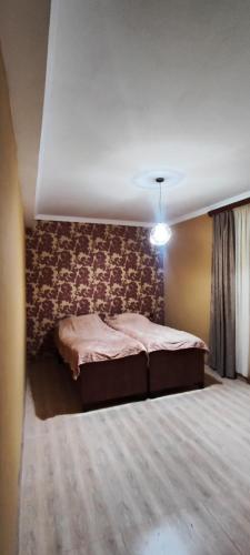 a bedroom with a bed with a floral accent wall at Nino in Kaspi