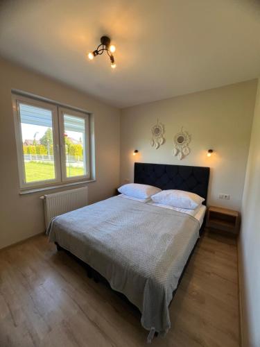 a bedroom with a bed and two windows at Apartamenty Bursztynowe in Dębki