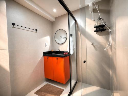 a bathroom with an orange cabinet and a mirror at Aurea Baulten by 123Quarto in Tambaú