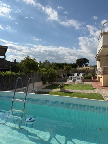 a swimming pool with a chair next to a house at Bed and Breakfast Villa Teis in Quartu SantʼElena