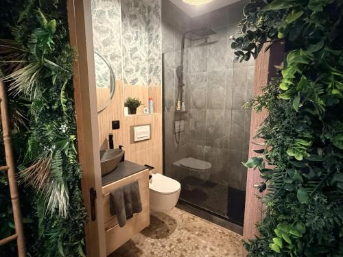 a bathroom with a toilet and a shower with plants at JUNGLE SUITE - Jacuzzi - Centre - Clim by Narbana in Narbonne