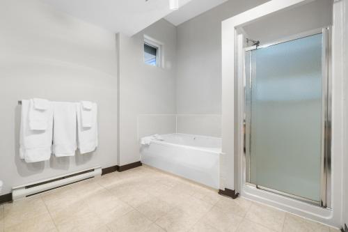 a white bathroom with a tub and a shower at The Lodge at Arrow Lakes in Nakusp